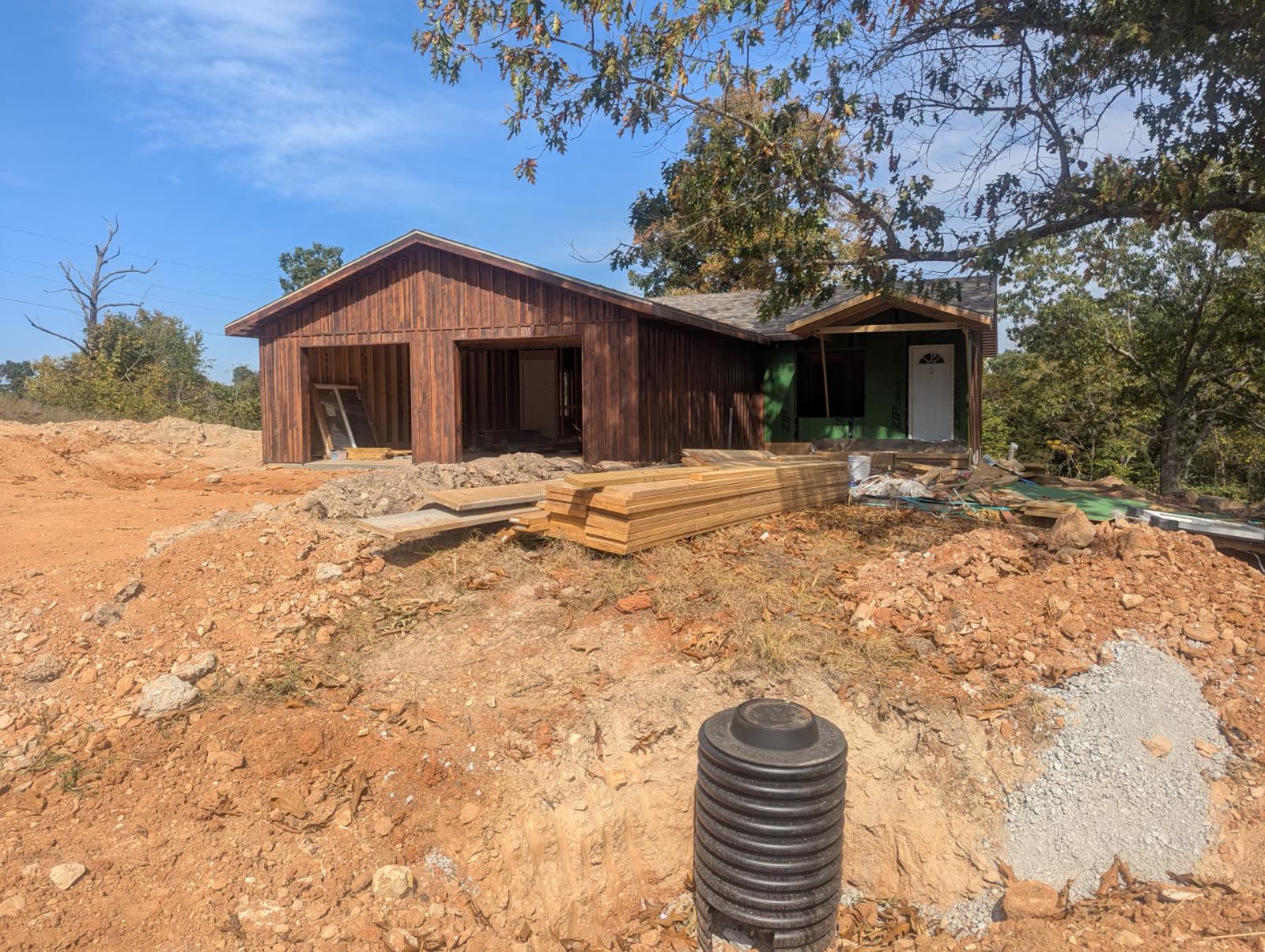 Front of the house with wood siding started and lumber staged