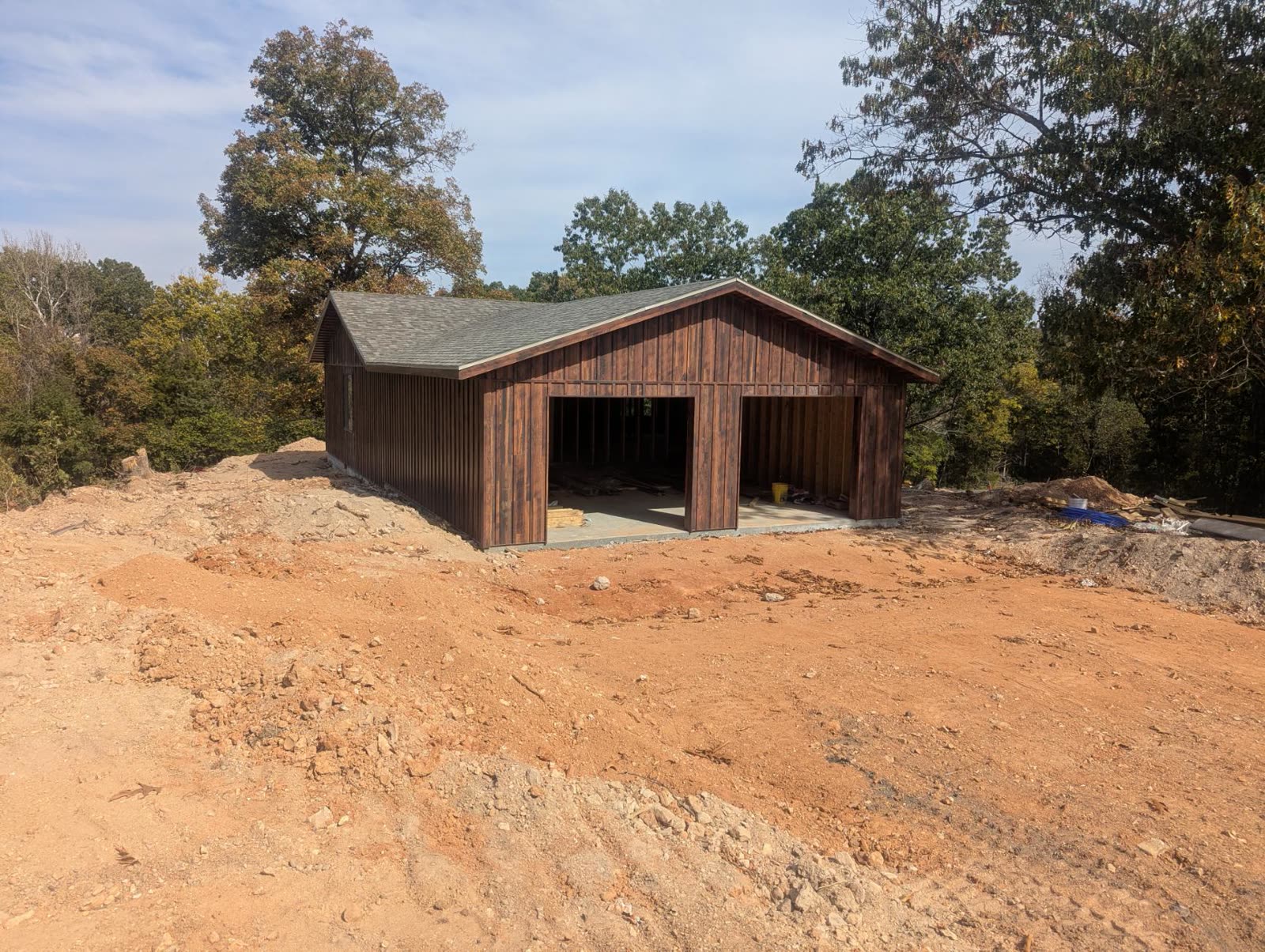 Garage bays open, wood siding and shingle roof in place