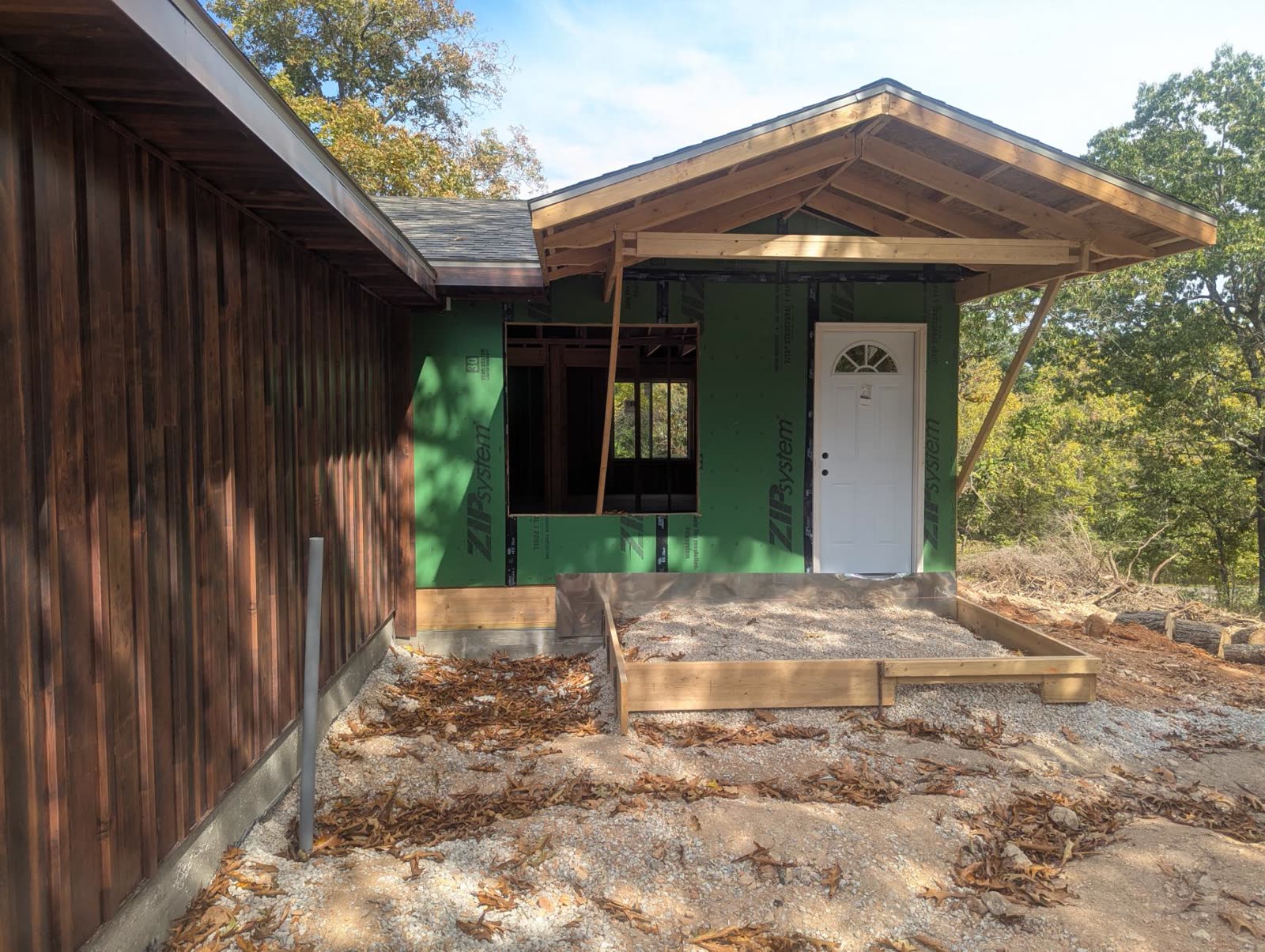 Front porch roof framed, white door set, wall still sheathed